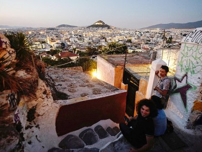 Des touristes profitent de la vue sur Athènes depuis le quartier Anafiotika situé dans la zone archéologique de l'Acropole, le 11 juillet 2018 en Grèce - LOUISA GOULIAMAKI [AFP]