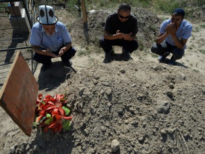 Des proches se recueillent sur la tombe de Bouroulaï Tourdaaly Kyzy, étudiante en médecine de 20 ans tuée par son kidnappeur, lors d'une cérémonie marquant les 40 jours de sa mort, le 28 juin 2018 à Sokuluk, dans le nord du Kirghizstan - Vyacheslav OSELEDKO [AFP]