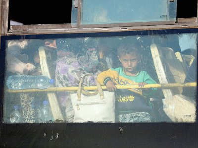 Des familles syriennes évacuées par bus de la province de Qouneitra arrivent au passage de Morek, le 21 juillet 2018 avant d'être emmenées vers les provinces d'Idleb et d'Alep - OMAR HAJ KADOUR [AFP]