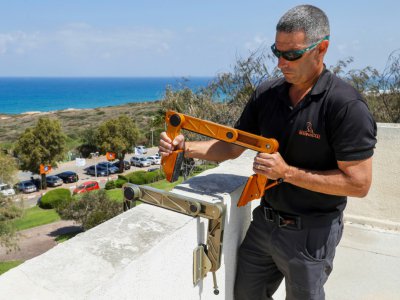 Idan Peretz accroche le crampon qu'il a baptisé RAFA (Roof Access Fast Anchor) sur une saillie du toit pour descendre en rappel, le 11 juin 2018 près de Netanya, en Israël - JACK GUEZ [AFP]
