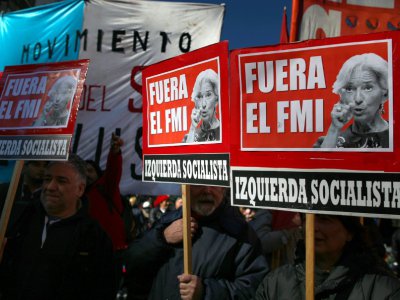 Des manifestants brandissent des pancartes "FMI dehors" lors du G20, le 21 juillet 2018 à Buenos Aires, en Argentine - AGUSTIN MARCARIAN [AFP]