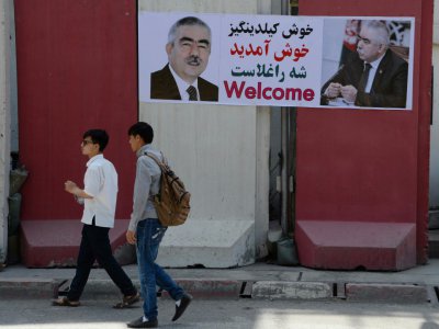 Des Afghans passent devant une banderole souhaitant la "bienvenue" au chef de guerre Abdul Rashid Dostum, de retour d'exil, le 22 juillet 2018. - NOORULLAH SHIRZADA [AFP]