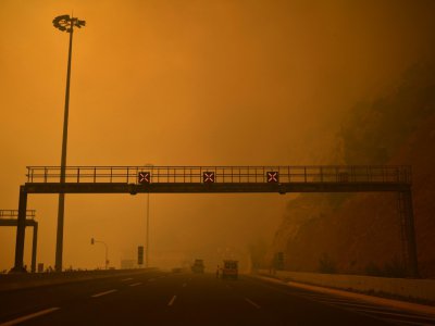 Photo prise le 23 juillet 2018 montrant une route enfumée par un incendie à Kineta près d'Athènes - ANGELOS TZORTZINIS [AFP]