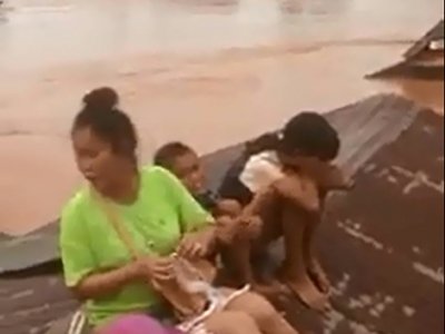 Sur cette capture d'écran d'une vidéo de ABC Laos le 24 juillet 2018, une femme et des enfants se sont réfugiés sur un toit entouré par les eaux déversées par la rupture du barrage de Xe-Pian-Xe. - Handout [ABC LAOS/AFP]