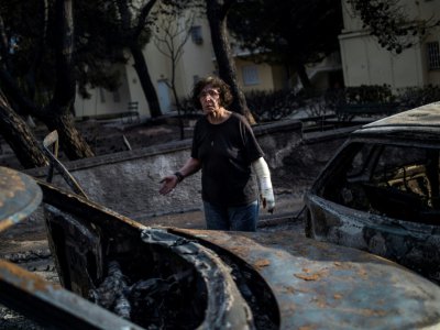 Une femme arpente une rue de Mati ravagée par les flammes, le 24 juillet 2018. - ANGELOS TZORTZINIS [AFP]