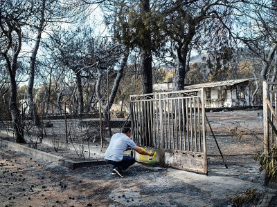 Un expert marque à la peinture le 26 juillet 2018 l'état d'une maison touchée par l'incendie dans le village de Neos Voutzas, près d'Athènes. - ANGELOS TZORTZINIS [AFP]