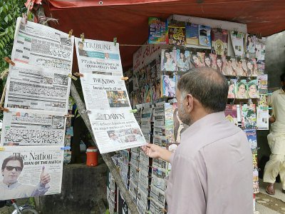 Un Pakistanais lit les titres de la presse dans un kiosque au lendemain des élections. - AAMIR QURESHI [AFP]