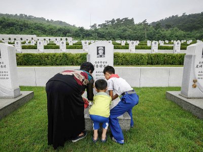 Une famille dépose des fleurs sur la tombe d'un soldat nord-coréen mort pendant la guerre de Corée, le 27 juillet 2018. - Ed JONES [AFP]