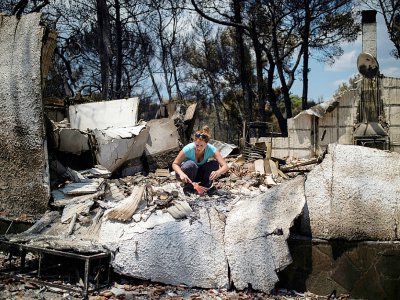 Une femme tente de récupérer quelques effets personnels dans les décombres de sa maison, le 25 juillet 2017 à Neos Voutzas. - ANGELOS TZORTZINIS [AFP/Archives]