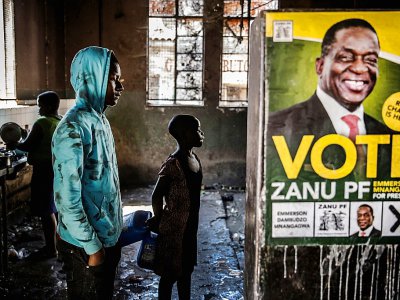 Dans une banlieue d'Harare, le 27 juillet 2018, un jeune homme attend devant une affiche représentant le président zimbabwéen Emmerson Mnangagwa, patron de la Zanu-PF, le parti au pouvoir - Luis TATO [AFP]