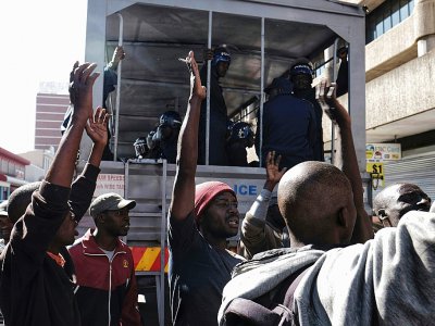 Des policiers anti-émeute sont stationnés devant la MDC, où des partisans de l'opposition dansent, sûrs de leur victoire, le 1er août 2018 à Harare - MARCO LONGARI [AFP]