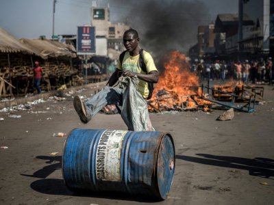 Un partisan de l'opposition au Zimbabwe pousse un bidon devant une barricade enflammée, le 1er août 2018 à Harare. - Luis TATO [AFP]