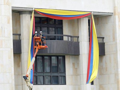 Des ouvriers mettent en place des banderoles aux couleurs du drapeau colombien sur la façade du palais de Justice de Bogota, à la veille de la cérémonie d'investiture du nouveau président, Ivan Duque, le 6 août 2018 - JOHN Vizcaino [AFP]