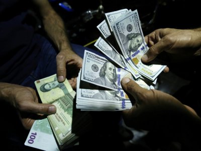 Un homme échange des rials iraniens contre des dollars américains à Téhéran, le 8 août 2018 - ATTA KENARE [AFP]