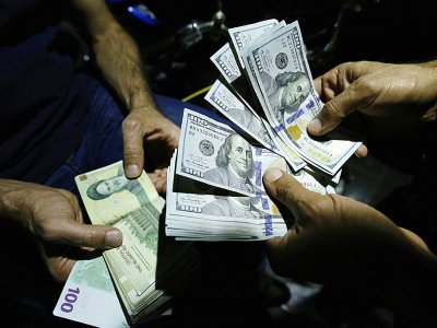 Le rial, la monnaie nationale iranienne, a chuté en raison des sanctions américaines. Images d'un homme échangeant ses rials contre des dollars le 8 août à Téhéran - ATTA KENARE [AFP/Archives]