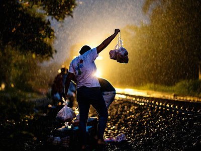 Des bénévoles lancent des sacs de nourriture aux migrants clandestins qui traversent à bord d'un train de marchandises le village de Las Patronas en direction des Etats-Unis, le 9 août 2018 dans l'Etat du Veracruz, au Mexique - RONALDO SCHEMIDT [AFP]