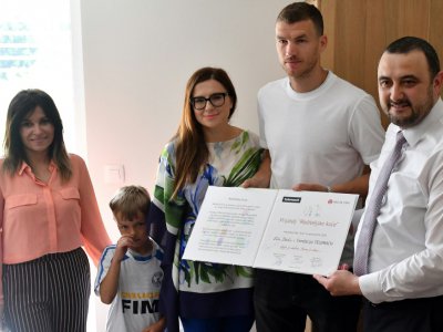 L'attaquant international Edin Dzeko (en t-shirt blanc) et le manager d'"Un coeur pour les enfants" Fikret Kubat à droite) posent après avoir signé un accord de financement de la maison parentale de Sarajevo, le 25 mai 2018 - ELVIS BARUKCIC [AFP]