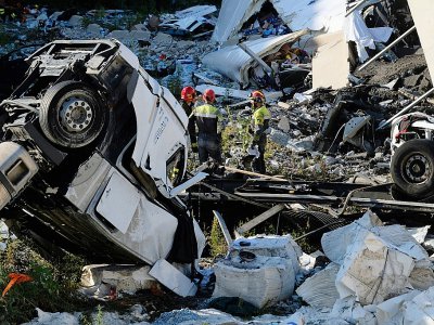 Des secouristes inspectent le 16 août 2018 les ruines et les débris laissés par l'effondrement d'une partie du pont Morandi à Gênes - ANDREA  LEONI [AFP]