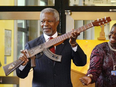 Kofi Annan, ancien secrétaire général de l'ONU, surnommé "rock star de la diplomatie" par certains, ici le 11 septembre 2007 à Vienne en Autriche, montre un fusil d'assaut AK-47 transformé en guitare - SAMUEL KUBANI [AFP/Archives]