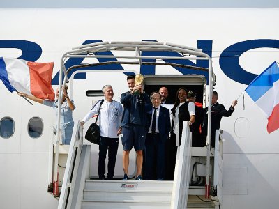 Le capitaine des Bleus Hugo Lloris brandit le trophée de champion du monde aux côtés de Didier Deschamps et Le Graët, le 16 juillet 2018 à l'Aéroport de Roissy - Lionel BONAVENTURE [AFP/Archives]