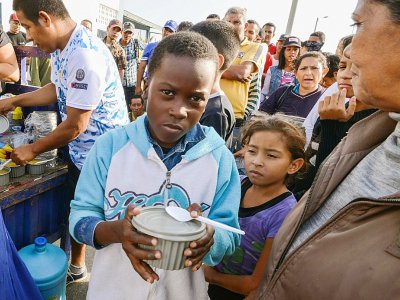 Des migrants vénézuéliens qui ont fui la crise économique dans leur pays reçoivent de l'aide et de la nourriture à Tumbes, au Pérou, à la frontière avec l'Equateur, le 23 août 2018 - CRIS BOURONCLE [AFP]
