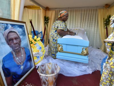 Une des filles de la centenaire décédée Anne M'Boua Ahoutié nettoie son cercueil à Adjakoutié, un petit village à l'ouest d'Abidjan, le 3 août 2018 - SIA KAMBOU [AFP]