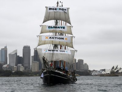 Un bateau portant la bannière "Rise for climate" (Debout pour le climat) entre dans le port de Sydney, en Australie, le 8 septembre 2018, au début de la journée d'action mondiale pour le climat - Saeed KHAN [AFP]