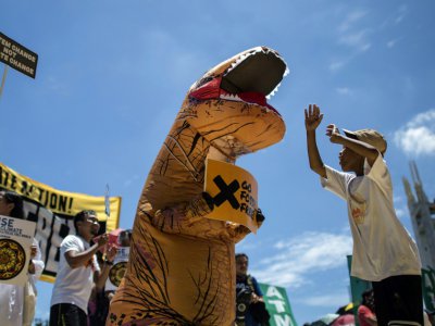 A Manille, le 8 septembre 2018, un manifestant habillé en dinosaure tient une pancarte "Go Fossil-free" ("Finissons-en avec les énergies fossiles"), au cours d'une manifestation dans le cadre de la journée mondiale "Rise for Climate" (Debout pour le - NOEL CELIS [AFP]