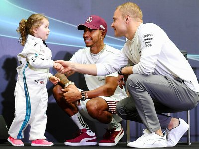 Les pilotes britanniques Lewis Hamilton (c) et Valtteri Bodas (d) parlent avec une jeune supportrice en marge du GP de Singapour, le 13 mai 2018 à Singapour - Manan VATSYAYANA [AFP]