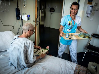 Une soignante apporte le repas à une patiente du Centre de cancérologie Léon Bérard à Lyon, le 10 septembre 2018 - JEAN-PHILIPPE KSIAZEK [AFP]