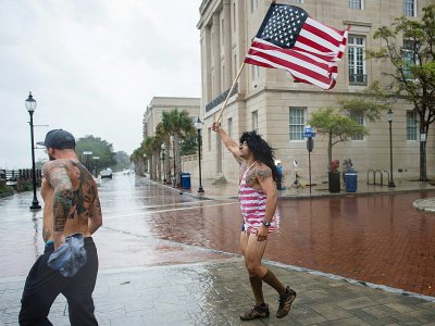 Un homme agite le drapeau américain face au vent et à la pluie quelques heures avant l'arrivée de l'ouragan Florence à Wilmington, en Caroline du Nord, le 13 septembre 2018 - ANDREW CABALLERO-REYNOLDS [AFP]