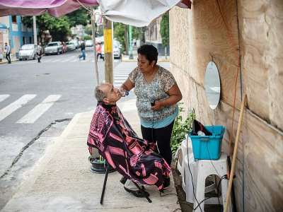 Une Mexicaine qui a perdu sa mère et son commerce dans le séisme de septembre 2017, travaille dans la rue, le 5 septembre 2018 à Mexico - Pedro PARDO [AFP]
