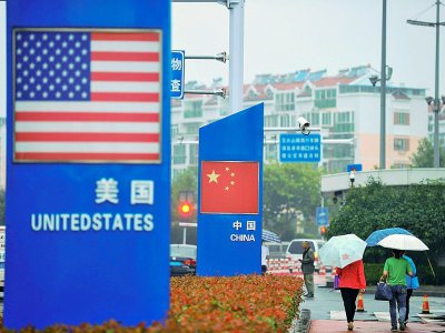 Des panneaux avec les drapeaux américain et chinois devant un magasin vendant des produits étrangers à Qingdao, le 19 septembre 2018 en Chine - STR [AFP/Archives]