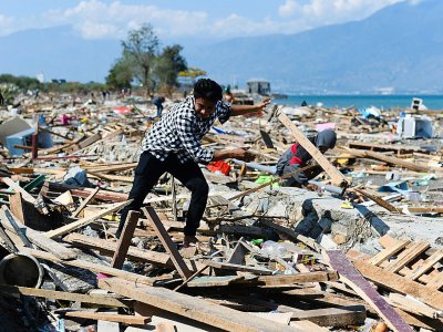 Un survivant du séisme meurtrier qui a frappé Palu sur l'île des Célèbes en Indonésie tente de récupérer des objets dans les décombres, le 1er octobre 2018 - Jewel SAMAD [AFP]