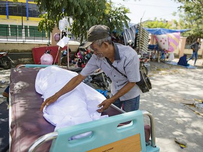 Un homme avec la dépouille de son fils le 2 octobre 2018 dans une morgue improvisée devant un hôpital de Palu, ville indonésienne frappée par un séisme et un tsunami - BAY ISMOYO [AFP]