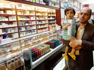 Un client d'une pharmacie de Téhéran portant dans ses bras un enfant, le 11 septembre 2018 dans la capitale iranienne - STRINGER [afp/AFP]