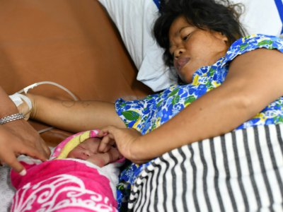 Dinar prend soin le 6 octobre 2018 de sa petite fille à laquelle elle a donné naissance sur un navire-hôpital après le terrible séisme suivi d'un tsunami qui a frappé Palu sur l'île des Célèbes en Indonésie - ADEK BERRY [AFP]