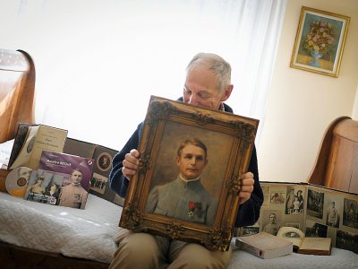 Le 8 octobre 2018, Patrice Retour, l'un des douze petits-enfants de Maurice et Yvonne Retour, pose avec le portrait de son grand-père, mort en 1915 à Nantes - LOIC VENANCE [AFP]