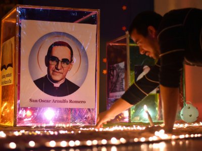 Un fidèle allume une bougie devant un portrait de l'archevêque Oscar Romero, à Ciudad Barrios, sa ville natale, au jour de sa canonisation le 14 octobre 2018 - Oscar RIVERA [AFP]