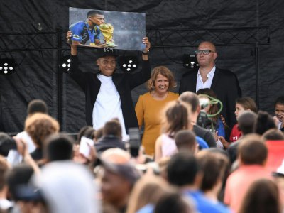 Kylian Mbappé brandit une photo de lui embrassant la Coupe du monde, le 17 octobre 2018 à Bondy - Anne-Christine POUJOULAT [AFP]