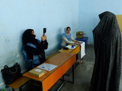 Une employée de la Commission électorale scanne le visage d'une votante lors des législatives, le 20 octobre 2018 à Hérat, en Afghanistan - HOSHANG HASHIMI [AFP]