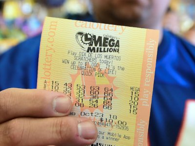 Un homme montre le ticket qu'il vient d'acheter pour le tirage du super jackpot de 1,6 milliard, le 23 octobre 2018 à Hawthorne, en Californie - Frederic J. BROWN [AFP]