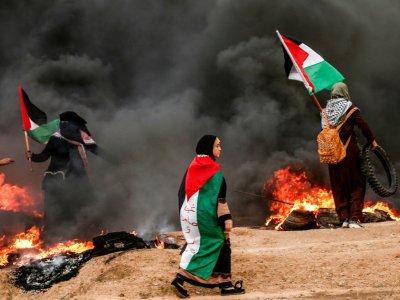 Des palestiniennes brandissent leur drapeau lors d'affrontements suite à une manifestation à l'est de Gaza, près de la frontière israélienne, le 26 octobre 2018 - MAHMUD HAMS [AFP]