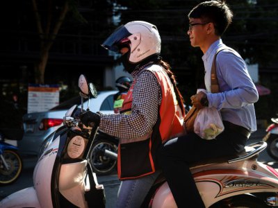 Une conductrice de moto taxi avec un passager à Bangkok, le 21 septembre 2018 - Lillian SUWANRUMPHA [AFP]