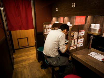 Un client prend son repas dans un compartiment réservé aux personnes seules dans un restaurant Tokyo, le 29 août 2018 - Behrouz MEHRI [AFP]
