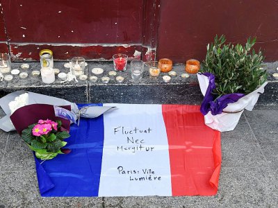 Des bougies, des fleurs et un drapeau français flanqué de la devise de Paris "Fluctuat nec Mergitur" sont déposé près du bar Le Carillon, le 14 novembre 2015 - DOMINIQUE FAGET [AFP]
