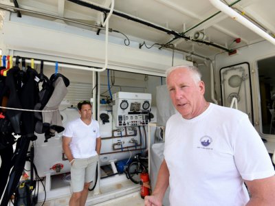 David Ruff (à droite), chercheur en archéologie marine, à bord d'un bateau utilisé pour des expéditions sous-marines à visées archéologiques dans un port en Albanie, le 17 juillet 2018 - Gent SHKULLAKU [AFP]
