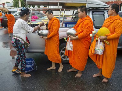 Des moines reçoivent des offrandes, le 23 octobre 2018 près d'un temple bouddhiste à Bangkok - Romeo GACAD [AFP]