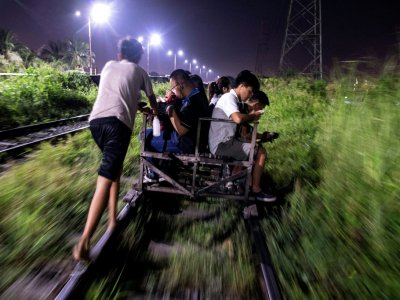Un "trolley boy" pousse des passagers sur son chariot qui emprunte la voie ferrée malgré les dangers, le 18 octobre 2018 à Manille - Noel CELIS [AFP]