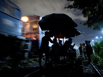 Des passagers poussés sur la voie ferrée par des "trolley boys", le 18 octobre 2018 à Manille - Noel CELIS [AFP]